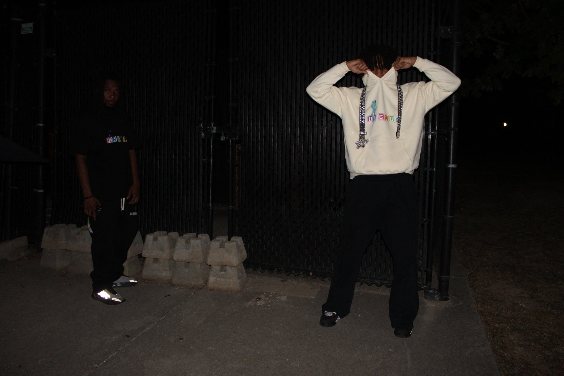 Person wearing a white hoodie with colorful text design in a dark setting